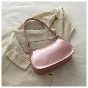 Detailed view of pink patent leather baguette bag with gold hardware on a beige blazer