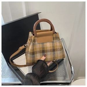 Detail of checkered tweed fabric and amber resin handle on a stylish crossbody bag
