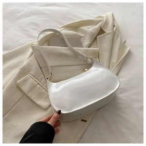 Detail of white patent leather baguette bag with gold hardware and smooth glossy finish