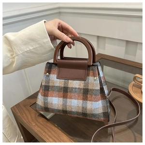 Detail shot of vintage plaid woolen handbag with brown leather handles and shoulder strap