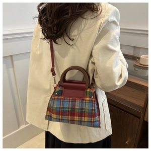 Detail of retro plaid wool handbag featuring a wooden handle and burgundy leather flap