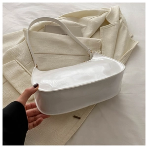 Detail of white patent leather baguette bag with minimalist gold hardware and shoulder strap
