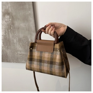 Close-up of brown plaid wool handbag with rigid handles and adjustable shoulder strap