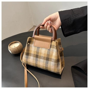 Close-up of retro plaid tweed handbag with brown leather trim and curved round handle