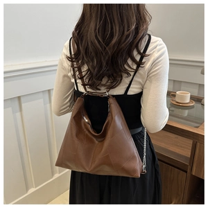 Détail d'un sac cabas vintage en patchwork marron avec coutures et chaîne métallique