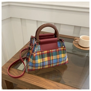 Detail view of the colorful plaid fabric texture and leather handle on this crossbody bag