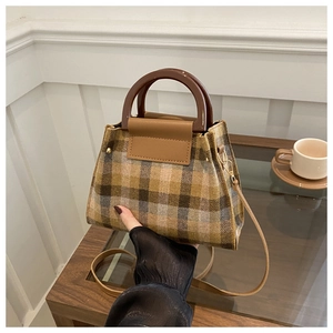 Detail of tweed plaid crossbody bag with resin handle and leather shoulder strap