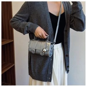 Detail of silver crocodile pattern mini barrel bag with metallic ball charm and handle