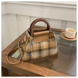 Detail of plaid tweed crossbody bag with brown resin handle on a coffee table