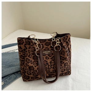 Close-up of leopard print tote bag featuring brown leather straps and gold metal chain links