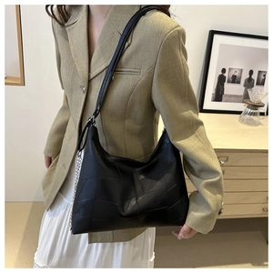 Détail du sac à bandoulière noir à patchwork géométrique avec chaîne argentée porté