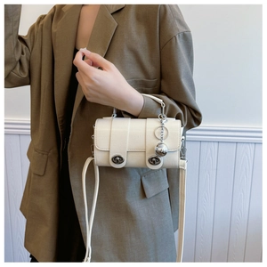 Detail of cream faux leather mini bag with silver ball charm and metallic twist locks