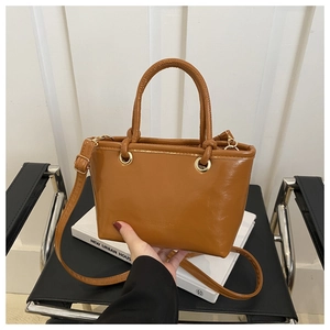 Detail of caramel leather bucket bag with gold metal eyelets and adjustable strap