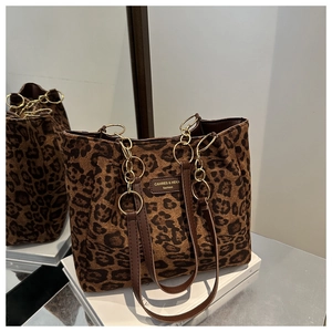Detail of leopard print tote featuring gold chain link handles and brand leather plaque