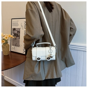 Detail of white crocodile pattern crossbody bag with silver ball charm and double twist locks