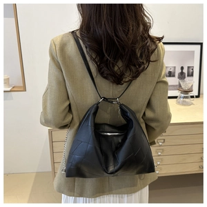 Gros plan du sac cabas en cuir patchwork noir avec chaîne argentée sur modèle