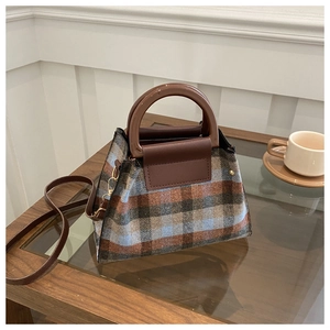 Detail of vintage plaid wool handbag with resin handle on a coffee table