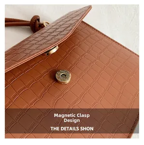 Detail of the magnetic snap closure on the brown crocodile pattern shoulder bag