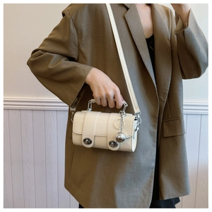 Close-up of beige PU crossbody bag with silver rotating locks and a metallic ball charm