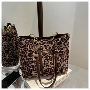 Macro view of leopard print tote bag with brown leather straps and gold metal rings