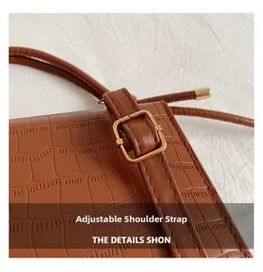 Detail view of brown crocodile texture handbag with adjustable strap and gold metal buckle
