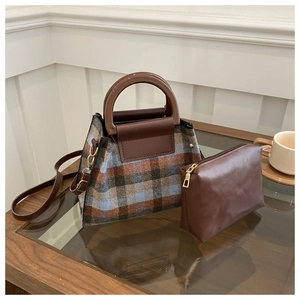 Detail of plaid tweed handbag and matching leather pouch on a glass tabletop