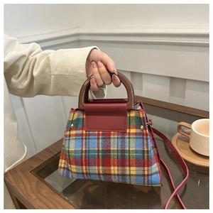 Detail of vintage plaid handbag with red leather flap and brown round handle
