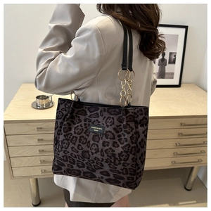Detail of leopard print tote bag with gold chain strap and logo on a chic beige blazer
