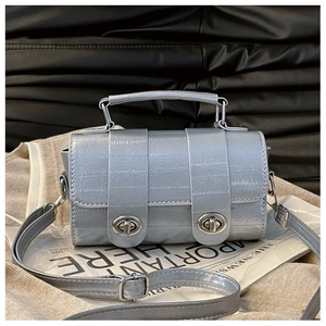 Macro shot of silver crocodile pattern mini handbag with metallic twist locks and handle