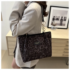 Detail of leopard print tote bag featuring a gold-toned chain strap and brand logo label