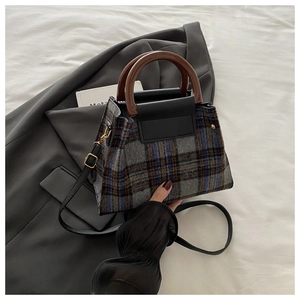 Detail of plaid handbag showing resin handle, textured fabric and adjustable strap