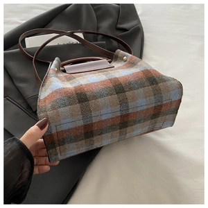Detail of vintage plaid tweed texture with leather handle and gold rivet hardware