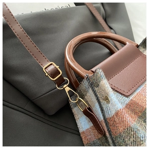 Close-up of vintage plaid fabric and gold-tone hardware on a crossbody handbag