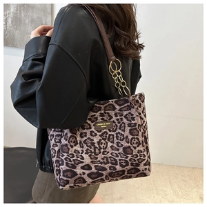 Detailed close-up of leopard print tote bag featuring gold chain and brown leather strap