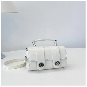 Detailed view of white crocodile pattern cylindrical handbag with silver twist locks