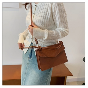 Detail view of brown crocodile texture on a vintage-style rectangular crossbody flap bag