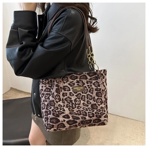 Detail of leopard print tote bag with leather straps and golden chain on a fashion model