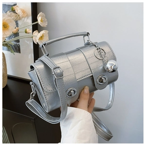 Close-up of silver metallic mini handbag featuring dual twist locks and orb pendant detail