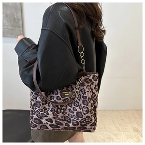 Detail of leopard print tote bag with brown leather straps and gold chain accents