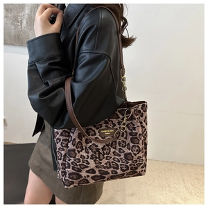Detail of leopard print tote bag with brown leather strap and brand label on shoulder