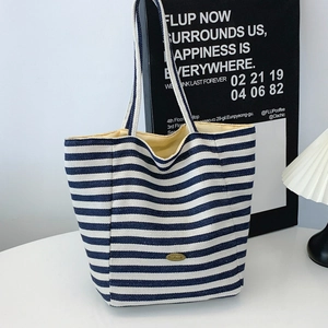 Large capacity blue and white striped canvas tote bag with white handles in a chic setting