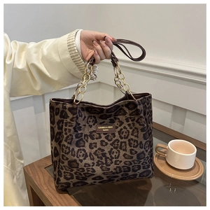 Detail of leopard print tote bag with gold chain strap and brand label on canvas