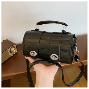 Detail of black glossy crocodile pattern handbag featuring double silver twist locks