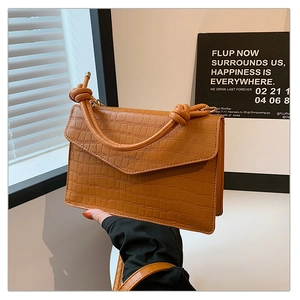 Detail of caramel brown croc-effect leather bag with unique knotted handle design