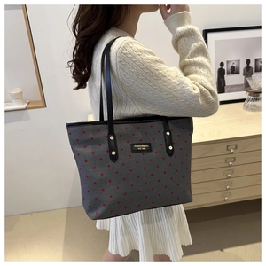 Detailed side view of large polka dot tote bag being worn on a shoulder
