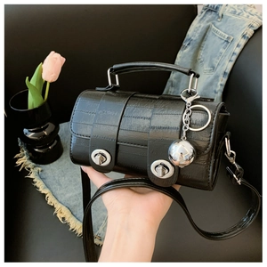 Close-up of black croc-embossed handbag with silver hardware and chic round metal charm