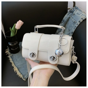 Detail of white crocodile pattern bag with dual silver locks and metallic ball charm