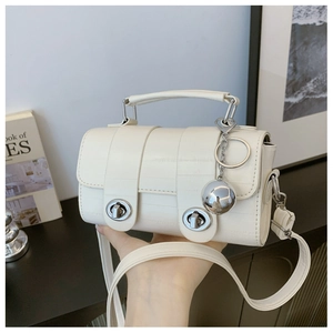 Close-up of cream crocodile pattern shoulder bag with silver ball charm and dual locks