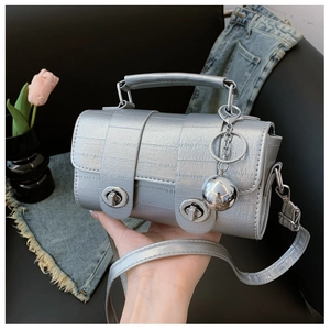 Close-up of silver crocodile embossed handbag featuring dual metal locks and mirror charm