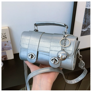 Detail of silver crocodile-patterned handbag with double turn-lock and metal ball charm